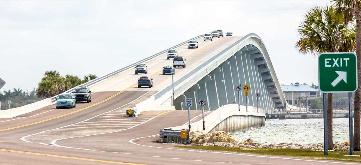 cars on arched bridge over waterway in florida