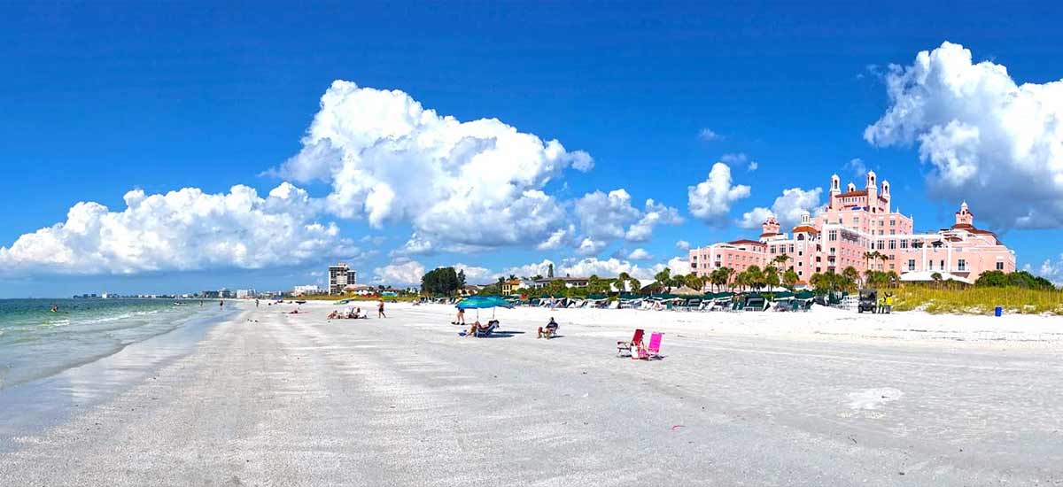 large pink hotel overlooking shoreline with beachgoers